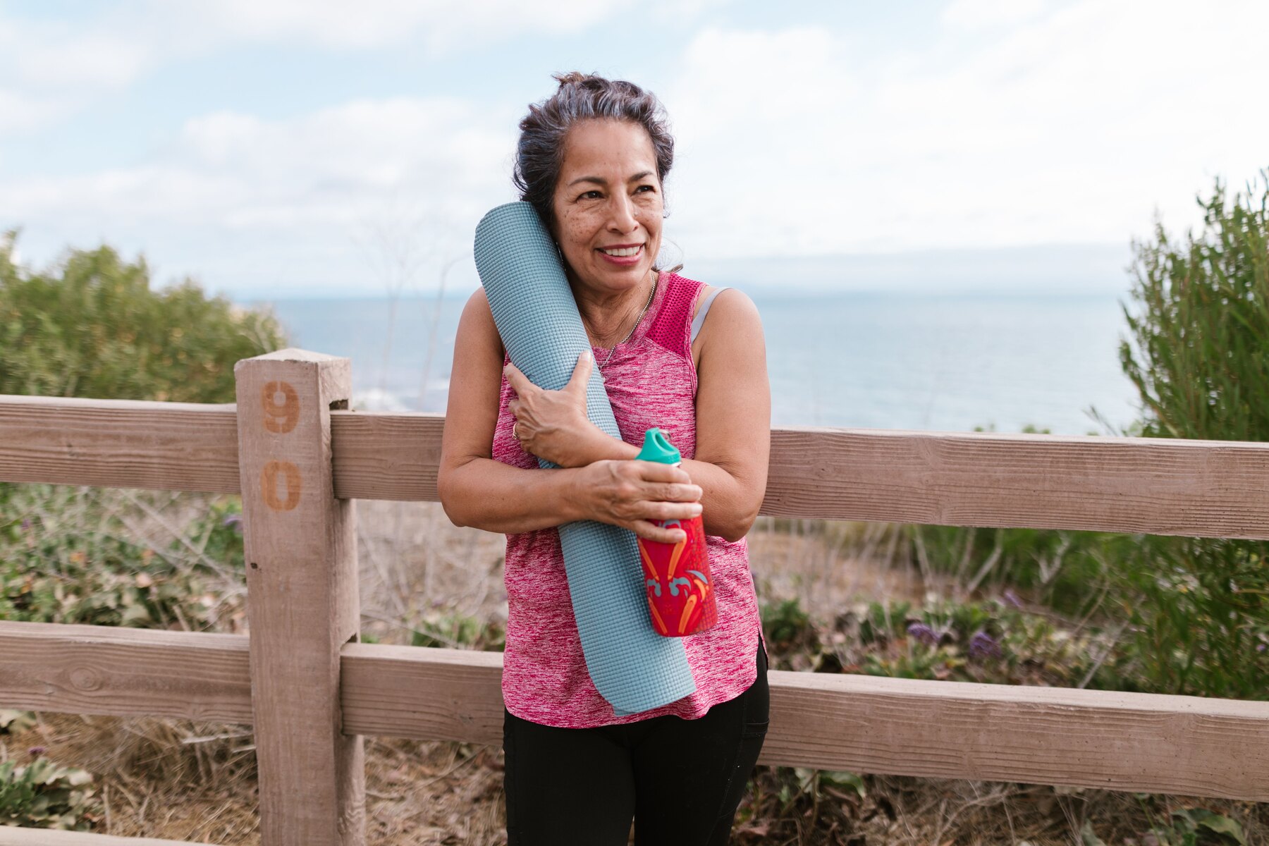 Kvinde med yogamåtte ved stranden som billede på en aktiv hverdag