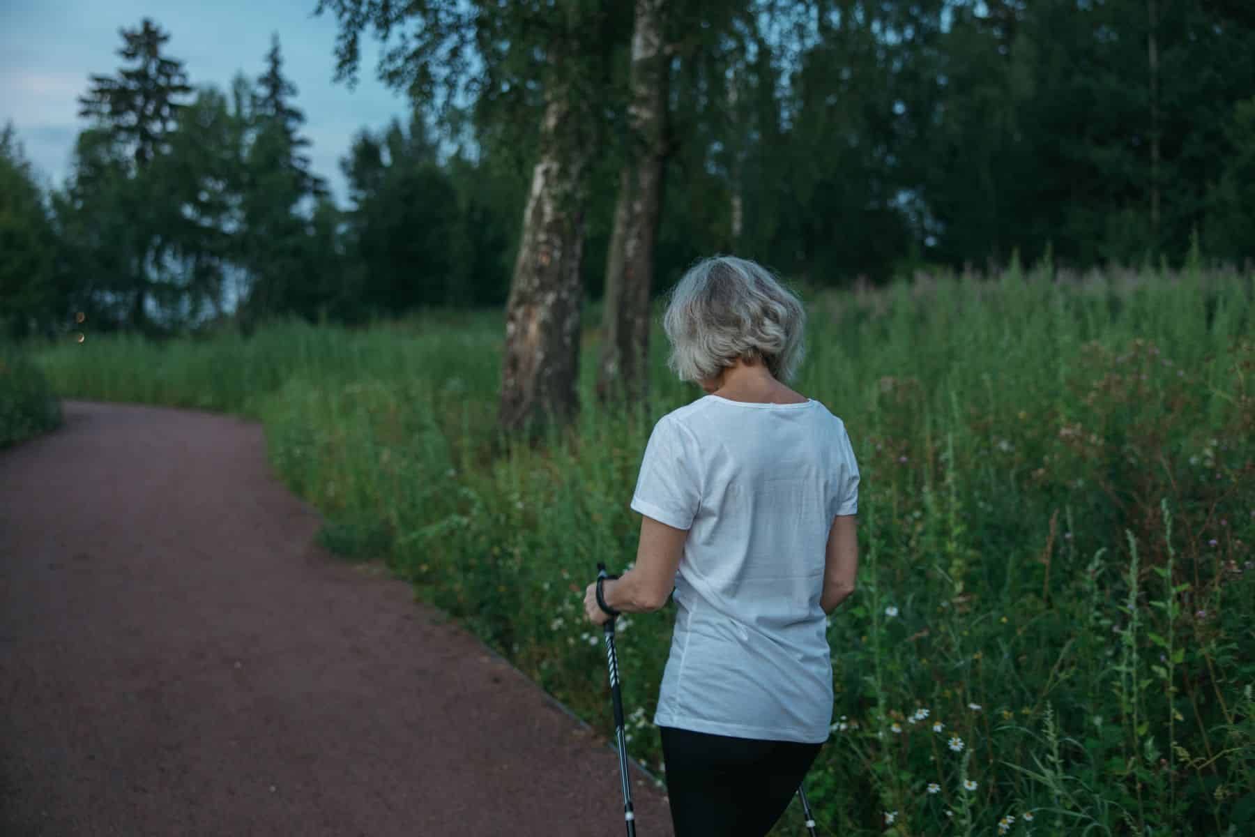 Ældre kvinde går tur med stave som en del af en aktiv hverdag