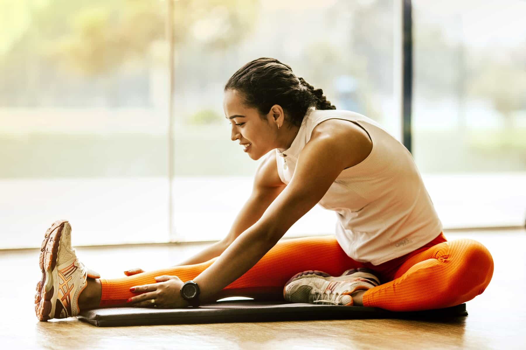Kvinde laver et roligt stræk på en yogamåtte derhjemme