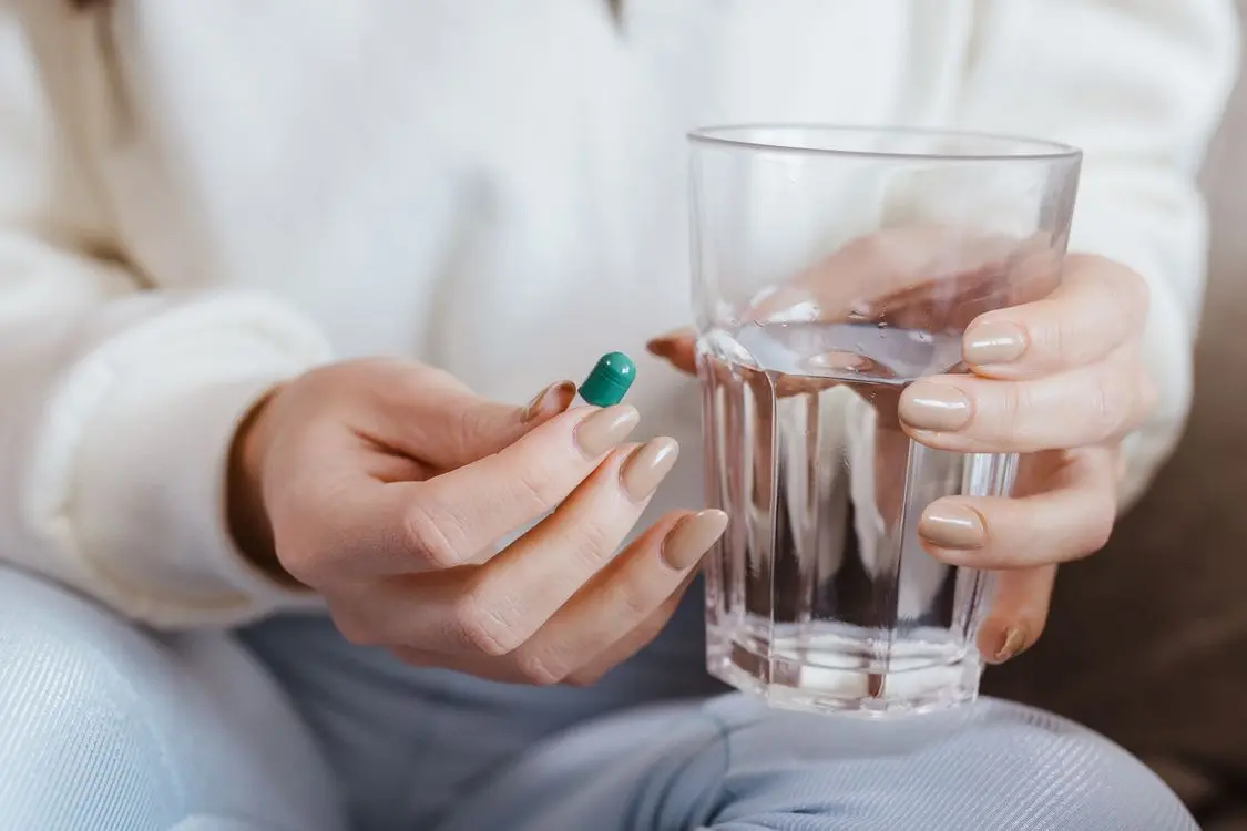 Person med en kapsel og et glas vand ved mulig medicinrelateret kvalme